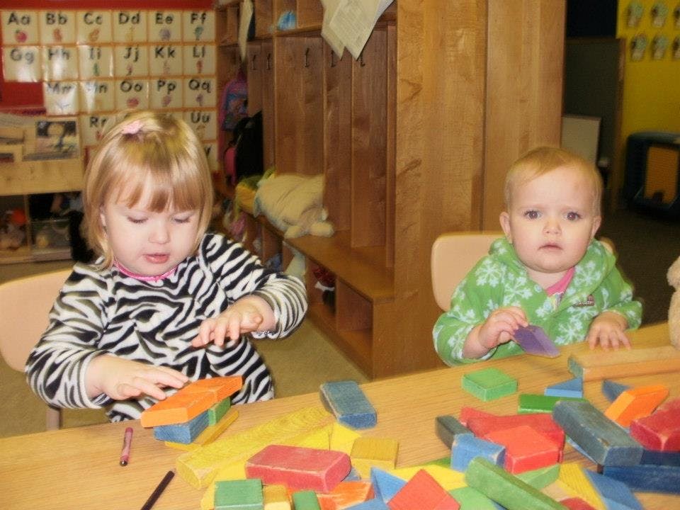 Two children playing with colorful blocks at a table in a classroom