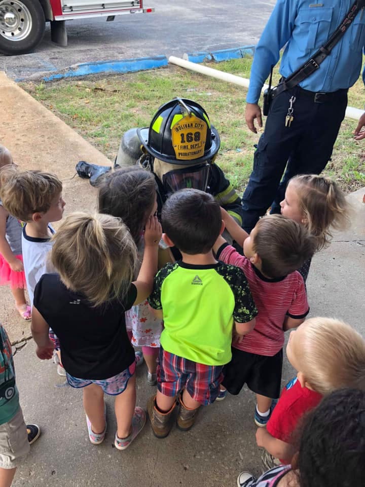 Children gathered around a person in firefighter gear