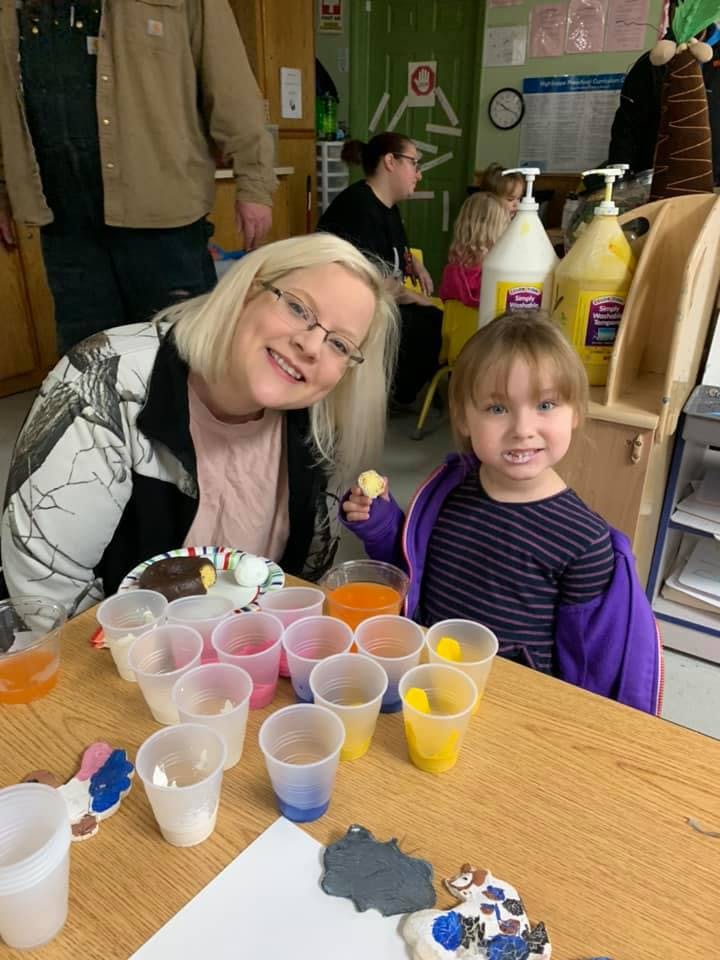 Person and child at a table with small cups and cookies