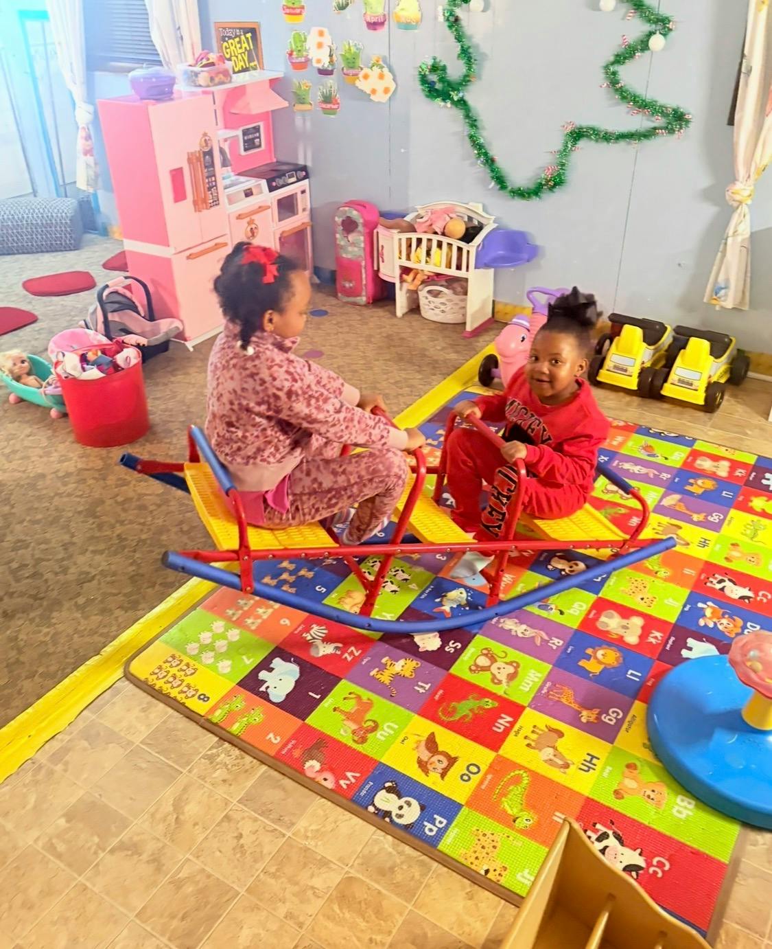 Two children on a red and yellow seesaw