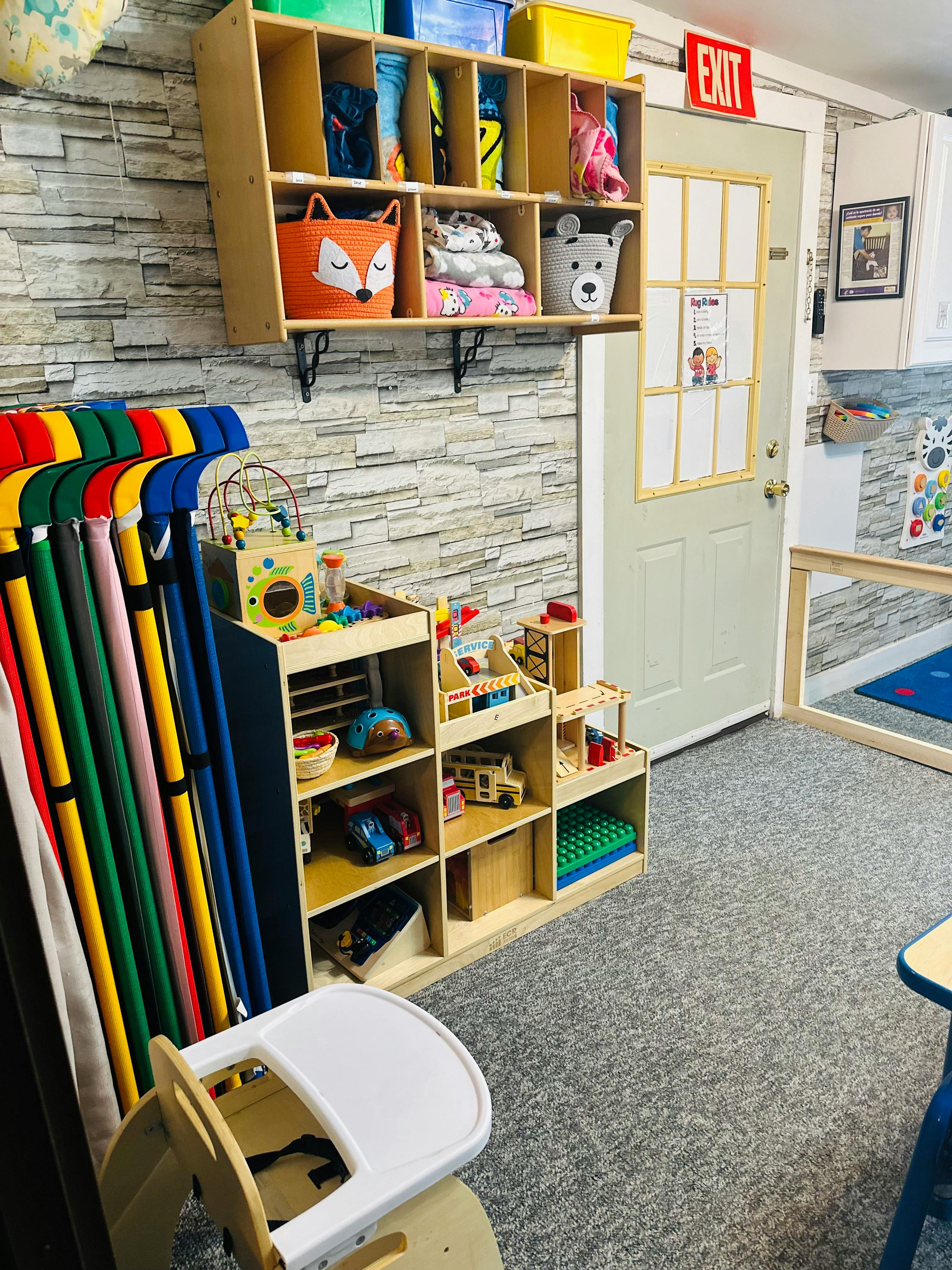 Children's play area with shelves of toys and an exit sign above a door