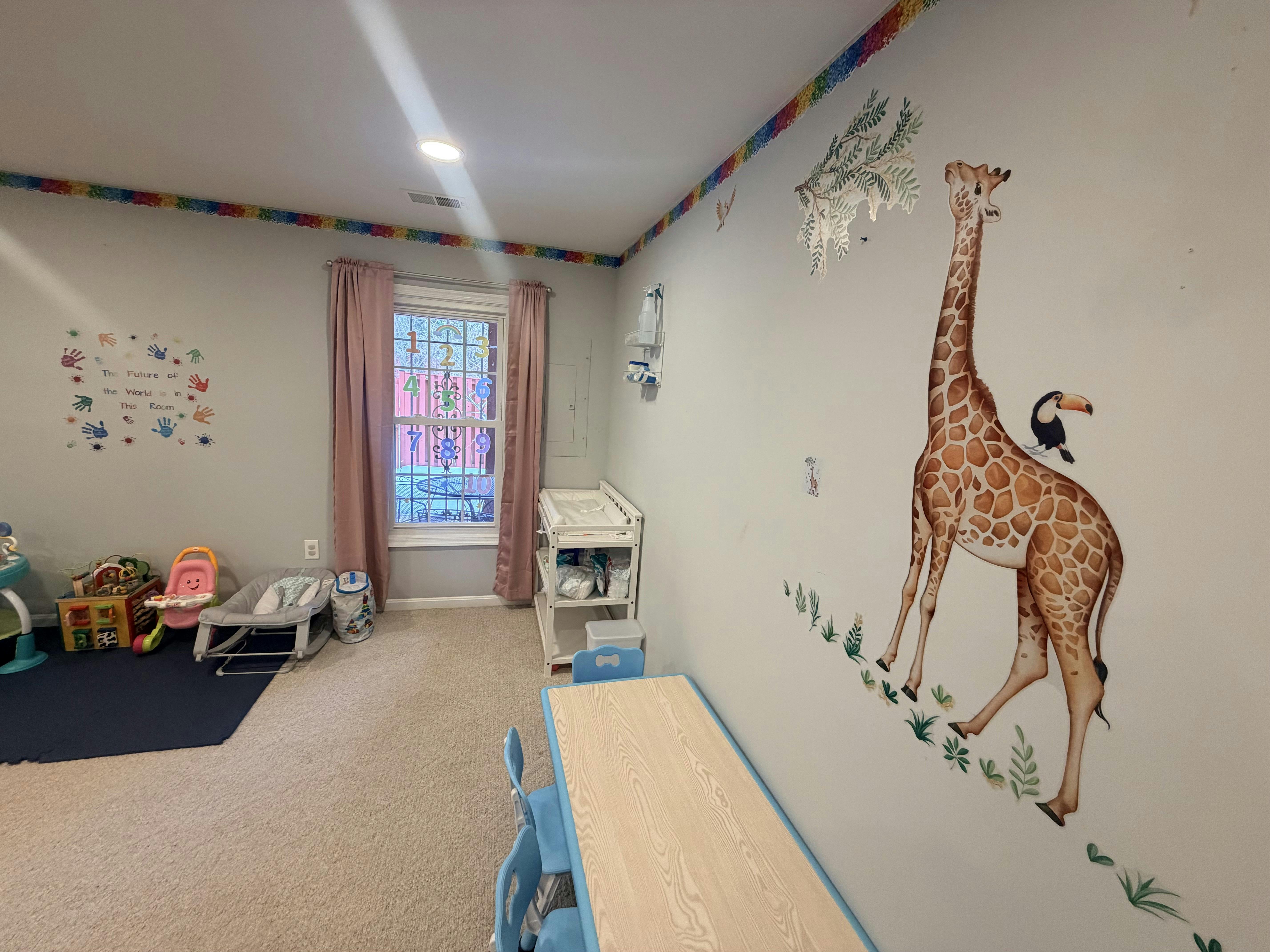 Child's room with a giraffe wall decal, playmat, and baby changing station