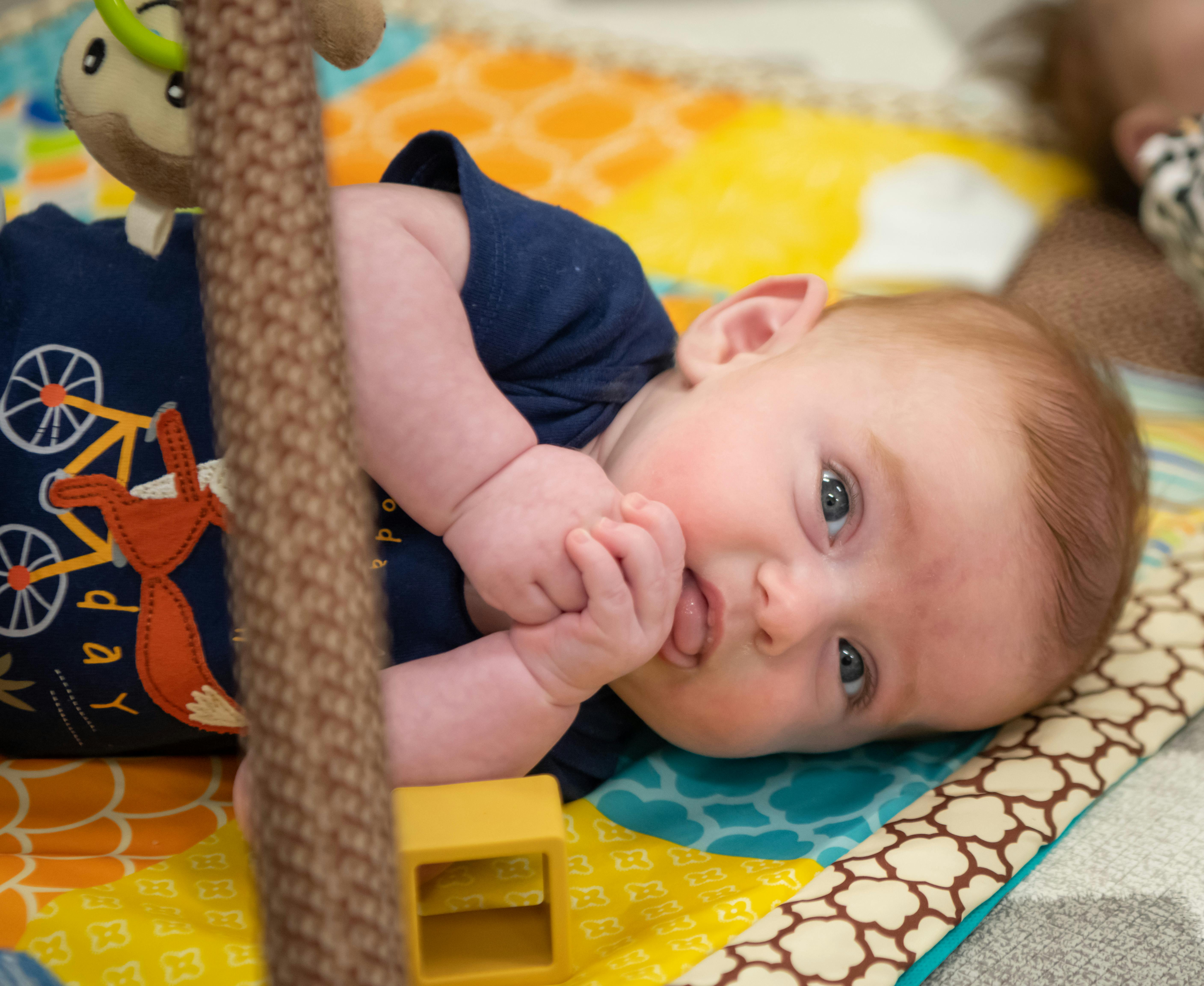 Child lying on a colorful mat, looking at the camera