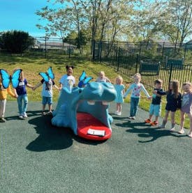 Children holding hands around a hippo play structure