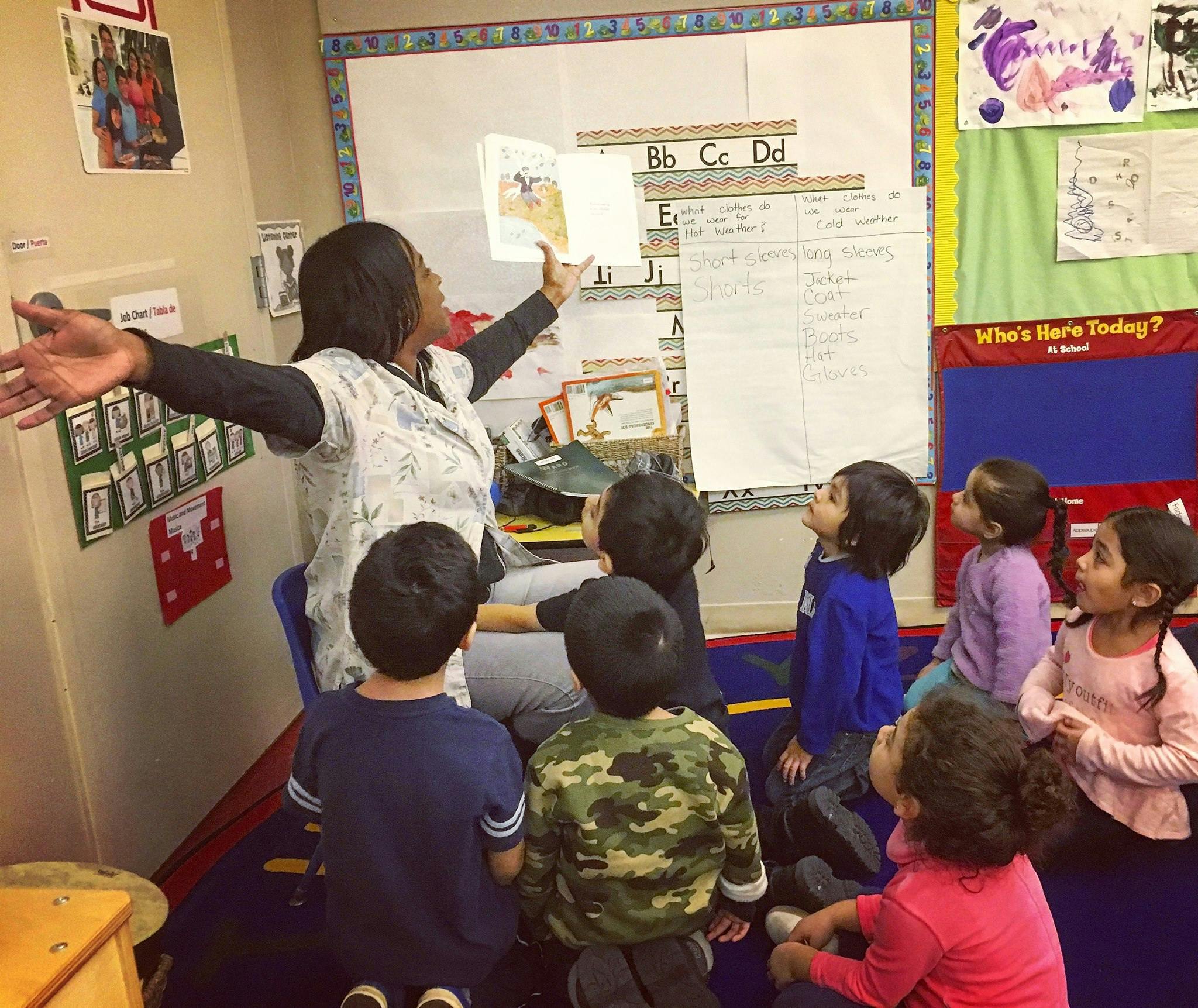 Person reading a book to a group of children in a classroom