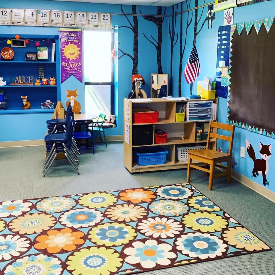 Classroom with a floral rug, blue walls, and a bookshelf