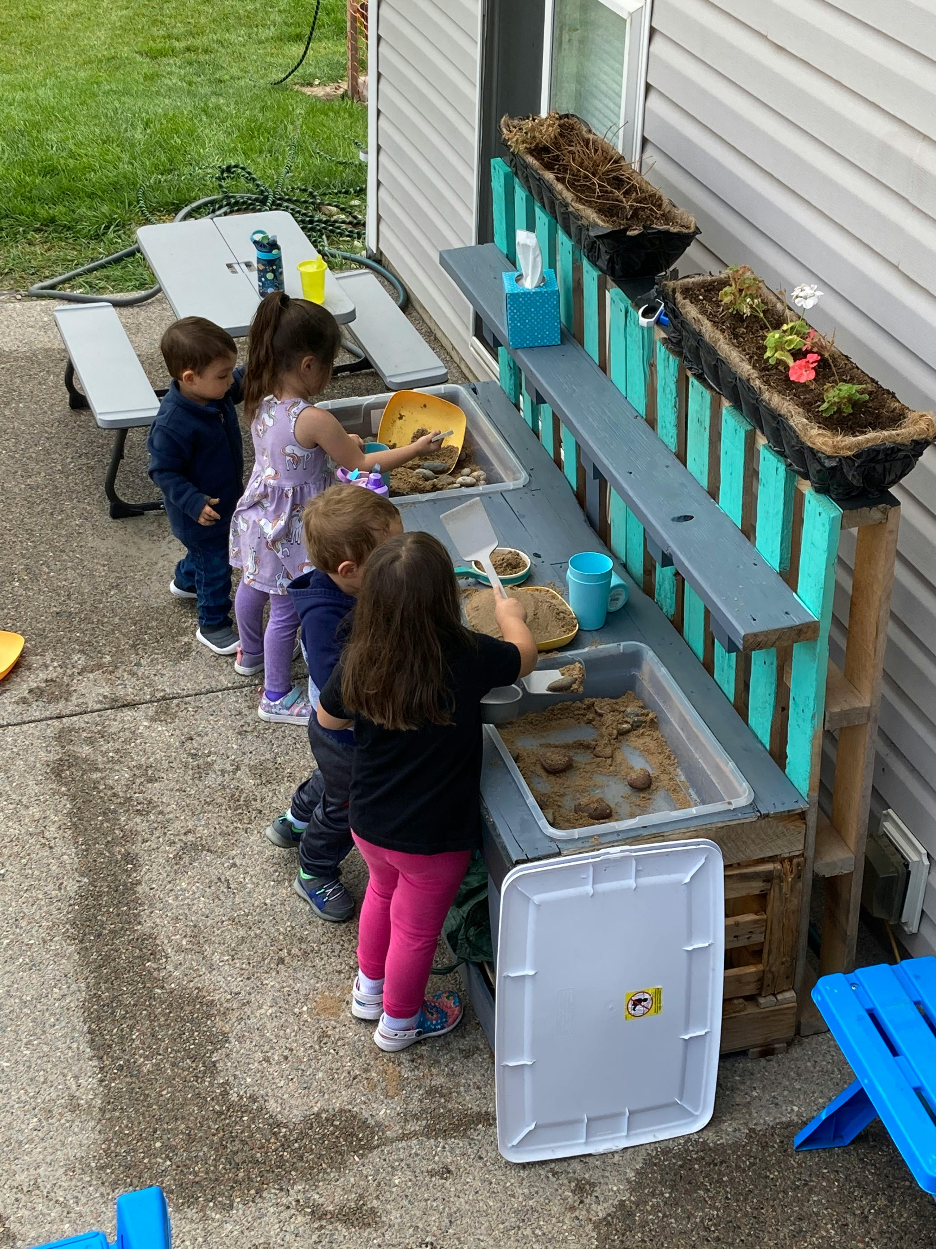 Children playing at an outdoor mud kitchen