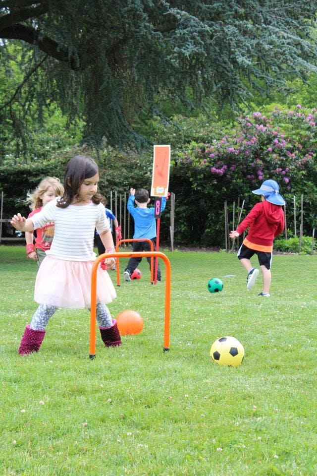 Children playing with balls and gates on a grassy field