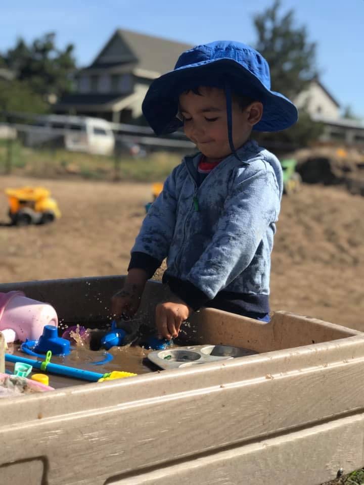 Child in a blue hat playing in a sandbox