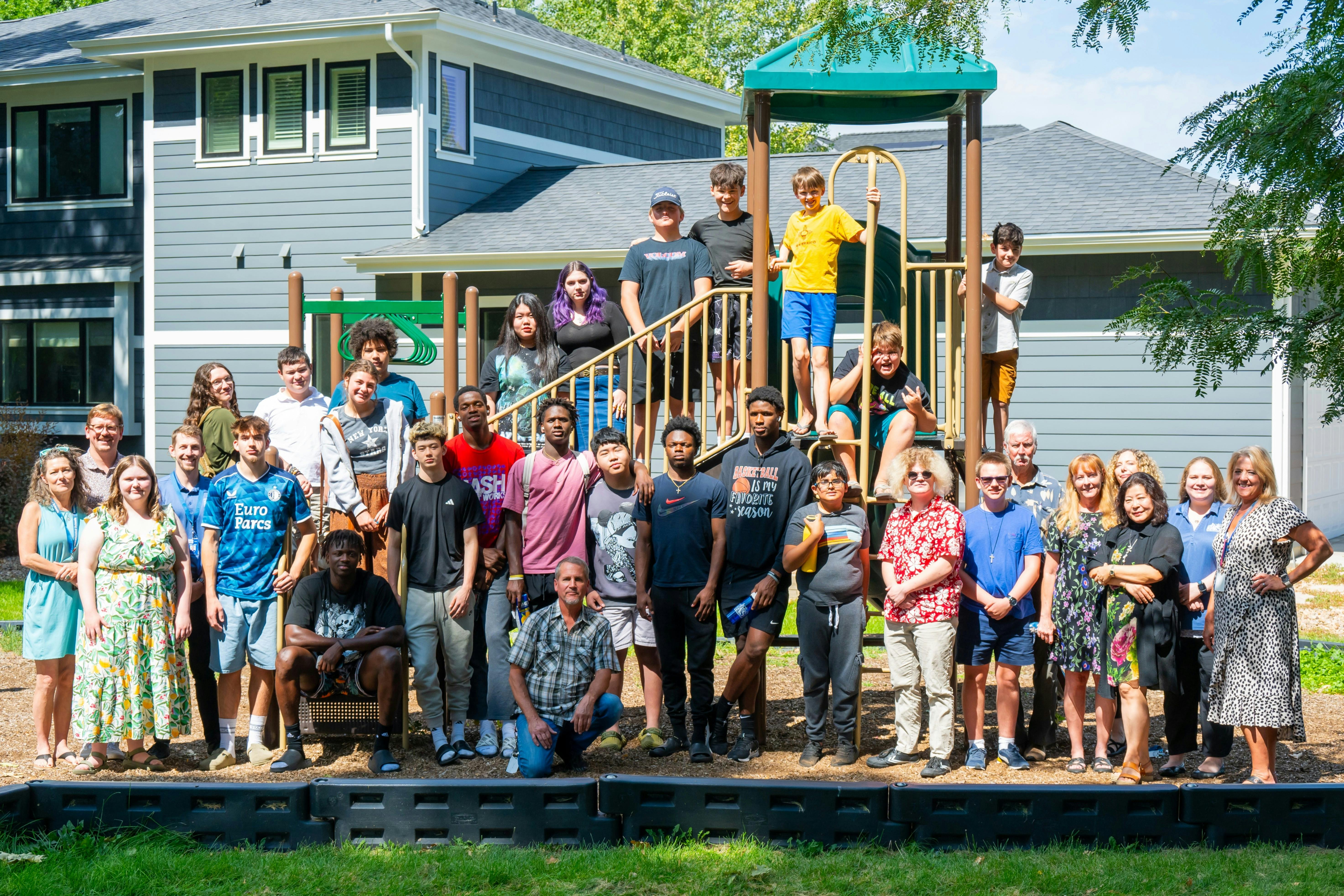 Large group of people standing on and around a playground structure