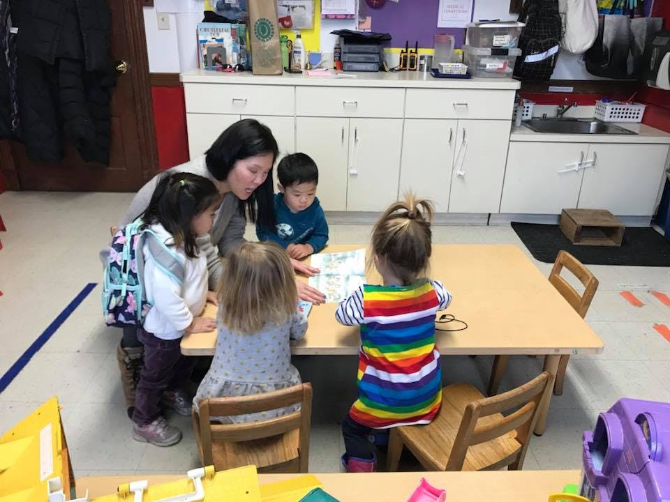Adult and children gathered around a table in a classroom