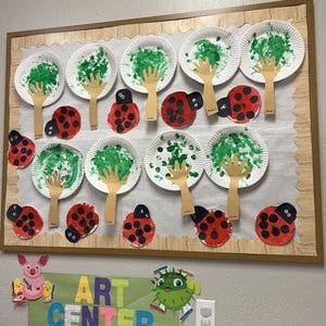 Children's art project with paper plates, green paint, and ladybugs