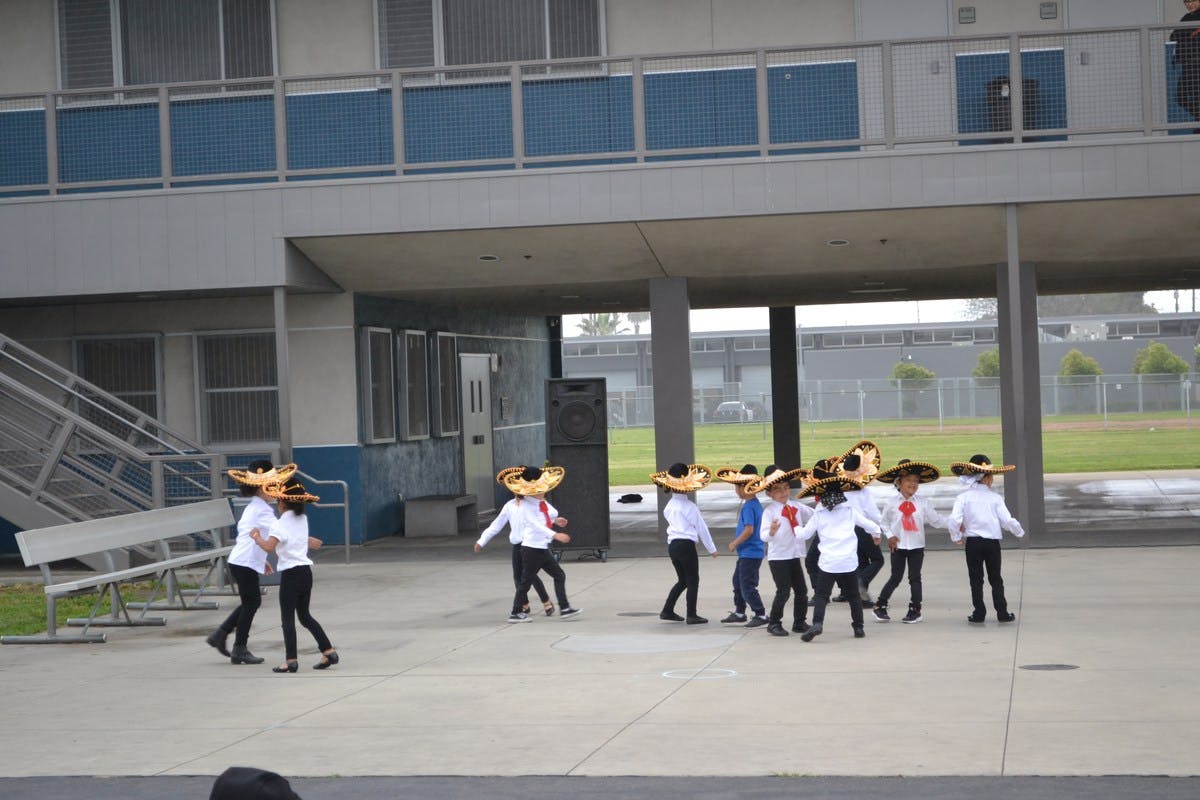 Children in sombreros and white shirts dancing outdoors