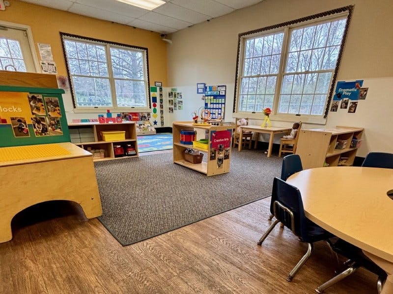 Empty classroom with small tables, chairs, and play areas