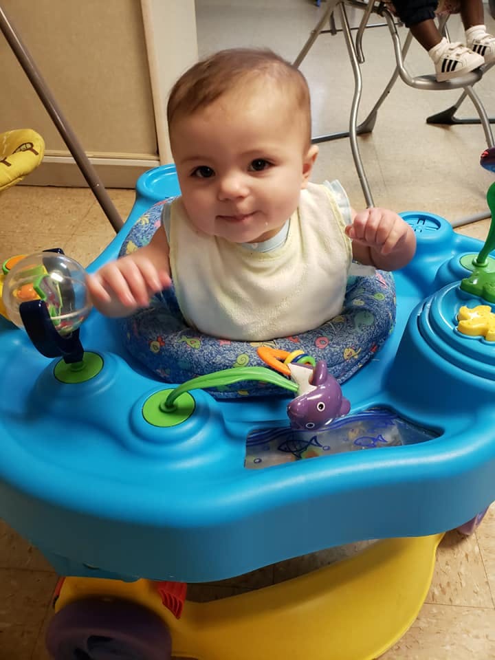 Child in a blue activity center with toys
