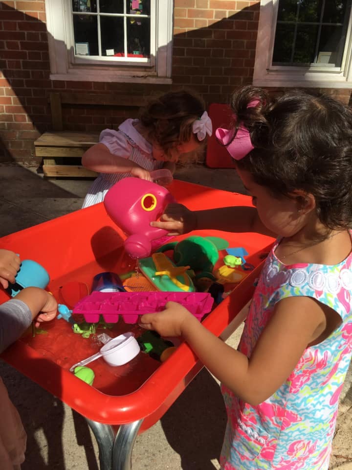 Two children playing with toys in a water table