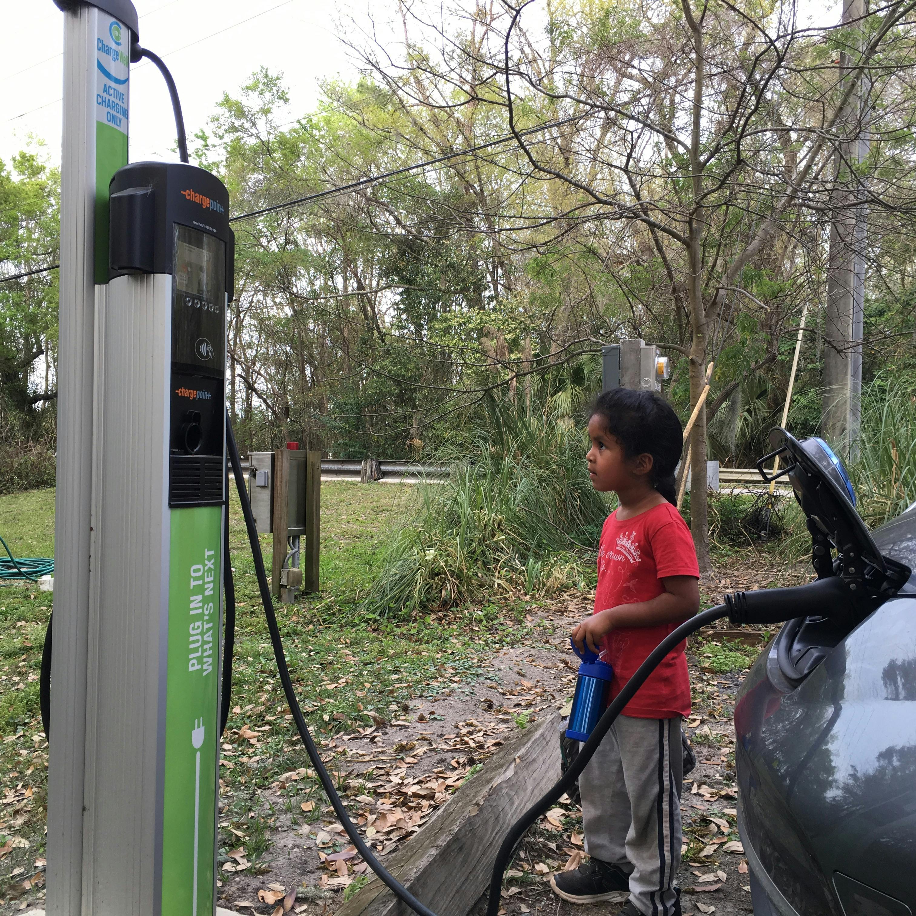 Child standing next to an electric vehicle charging station