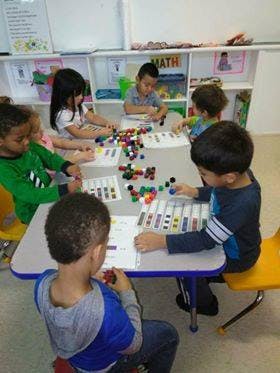 Children at a table playing with colorful manipulatives