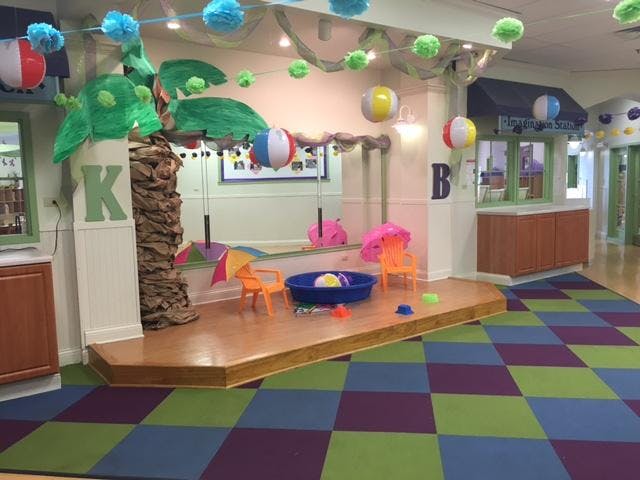 Playroom decorated with a palm tree, beach balls, and colorful floor tiles