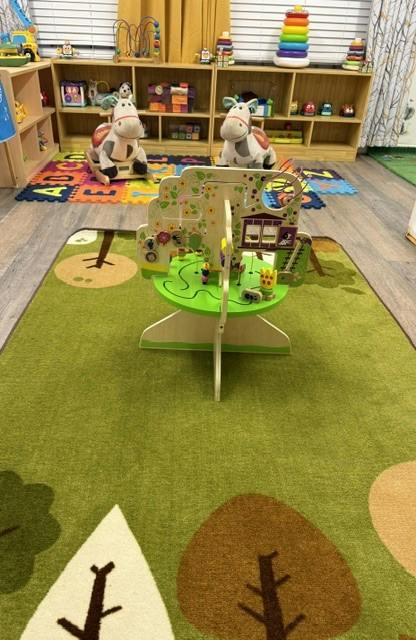 Wooden activity center on a tree-patterned rug in a playroom