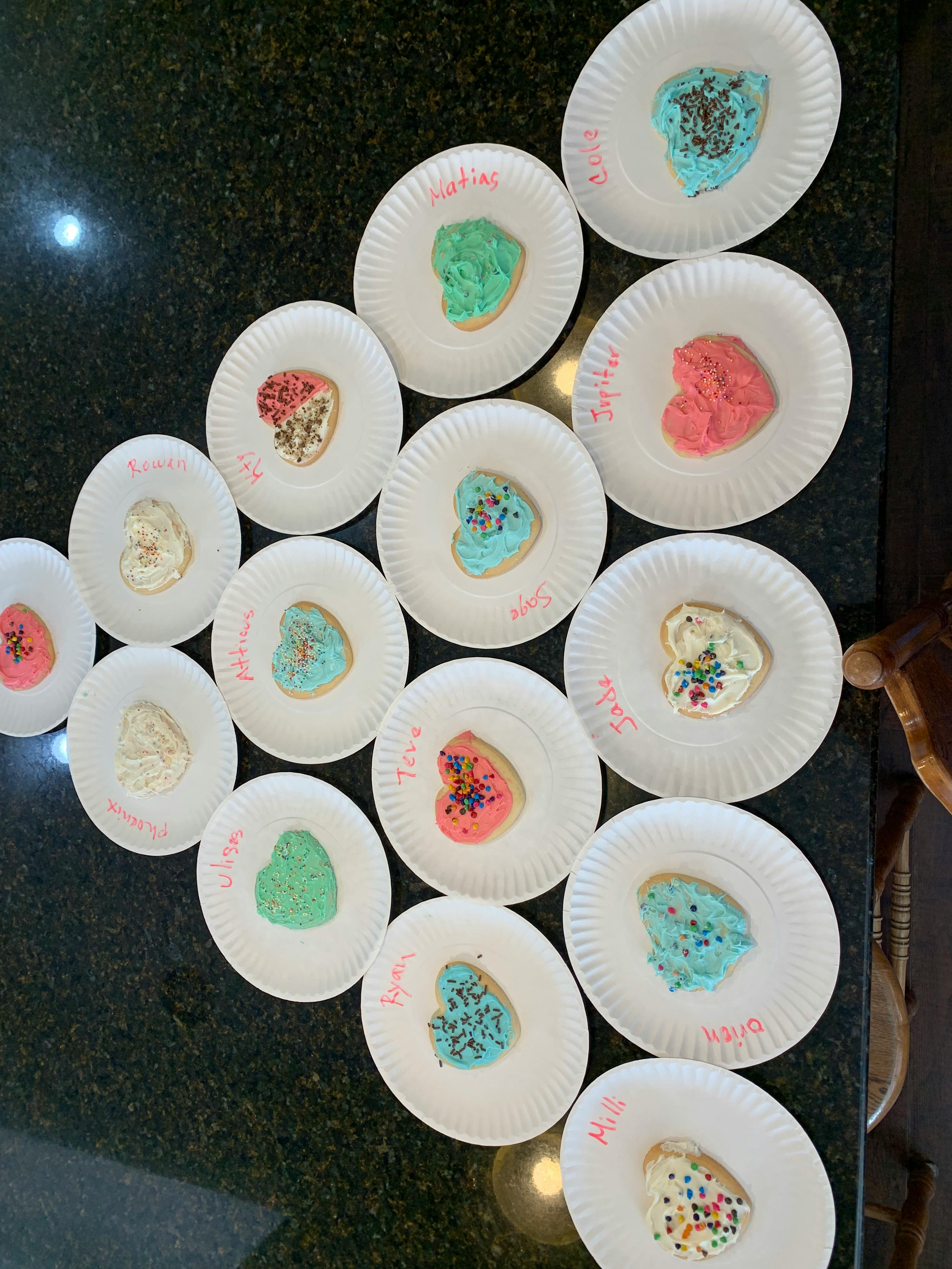 Heart-shaped cookies with frosting and sprinkles on paper plates