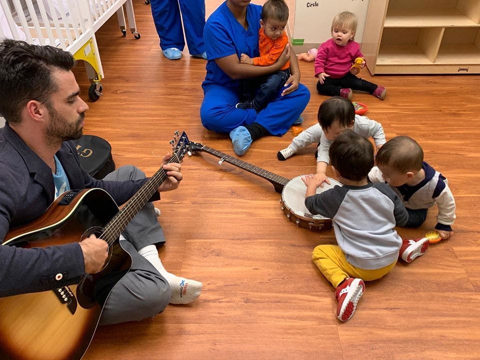 Person playing guitar for children gathered around a banjo