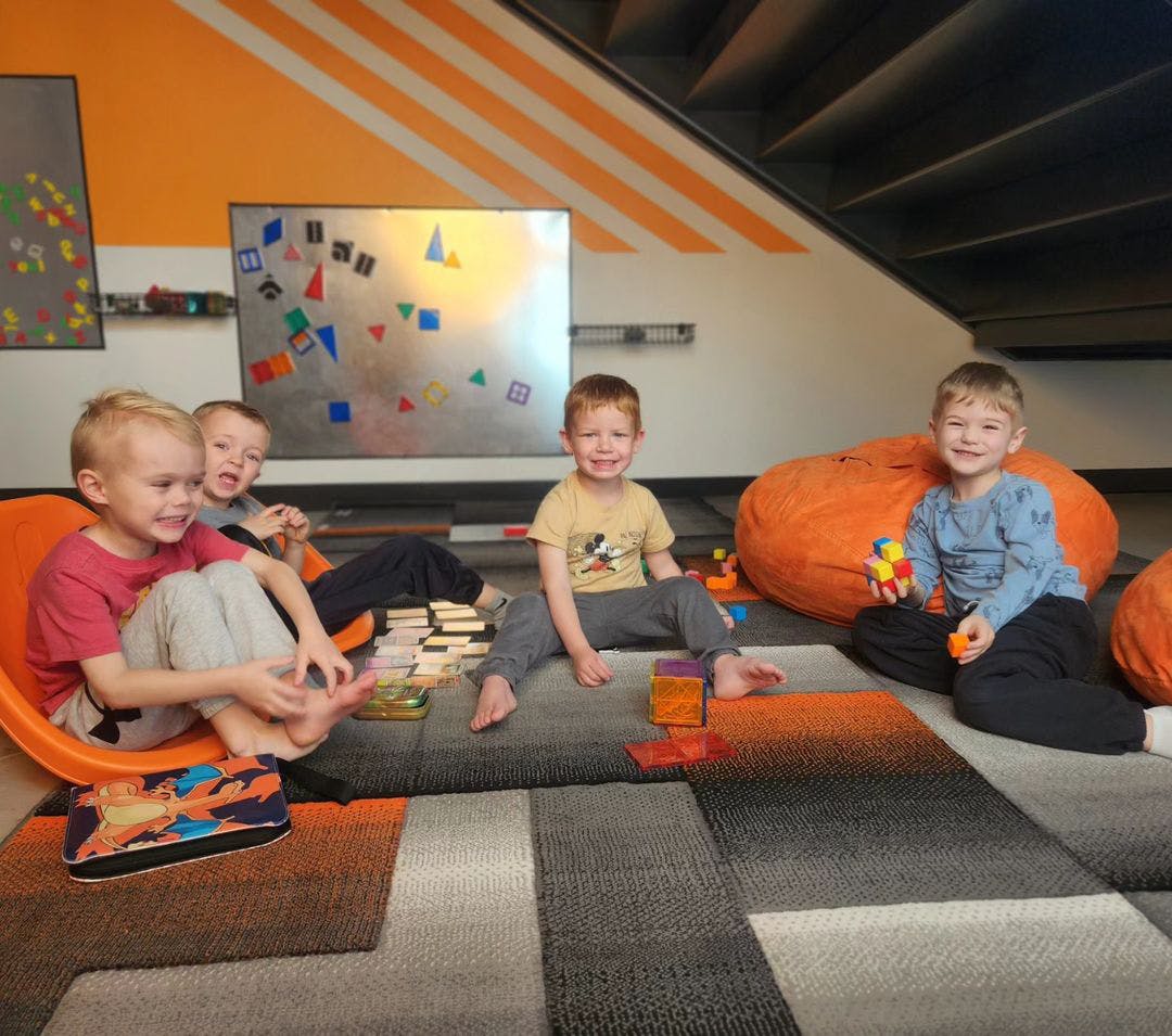 Four children sitting on a carpeted floor with toys