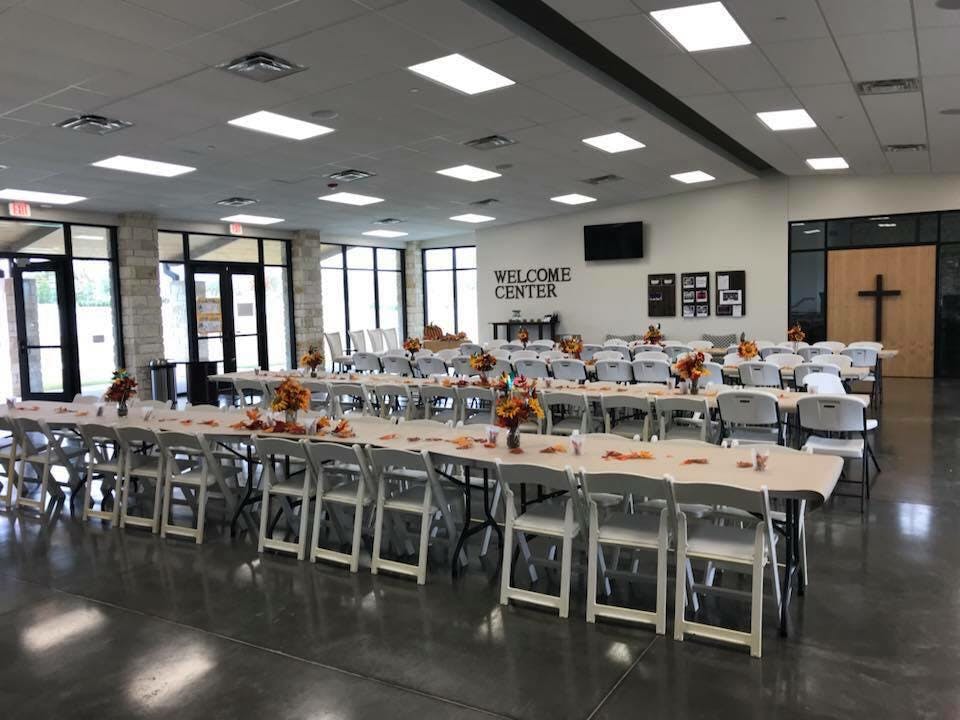 Long tables and chairs set up in a large room with a "Welcome Center" sign