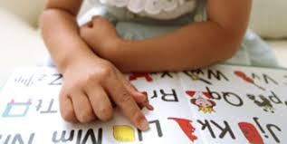 Child's hand pointing to letters on a learning mat