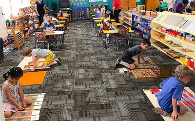 Children working on the floor and at desks in a classroom