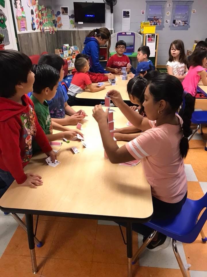 Children playing with cards at a table in a classroom