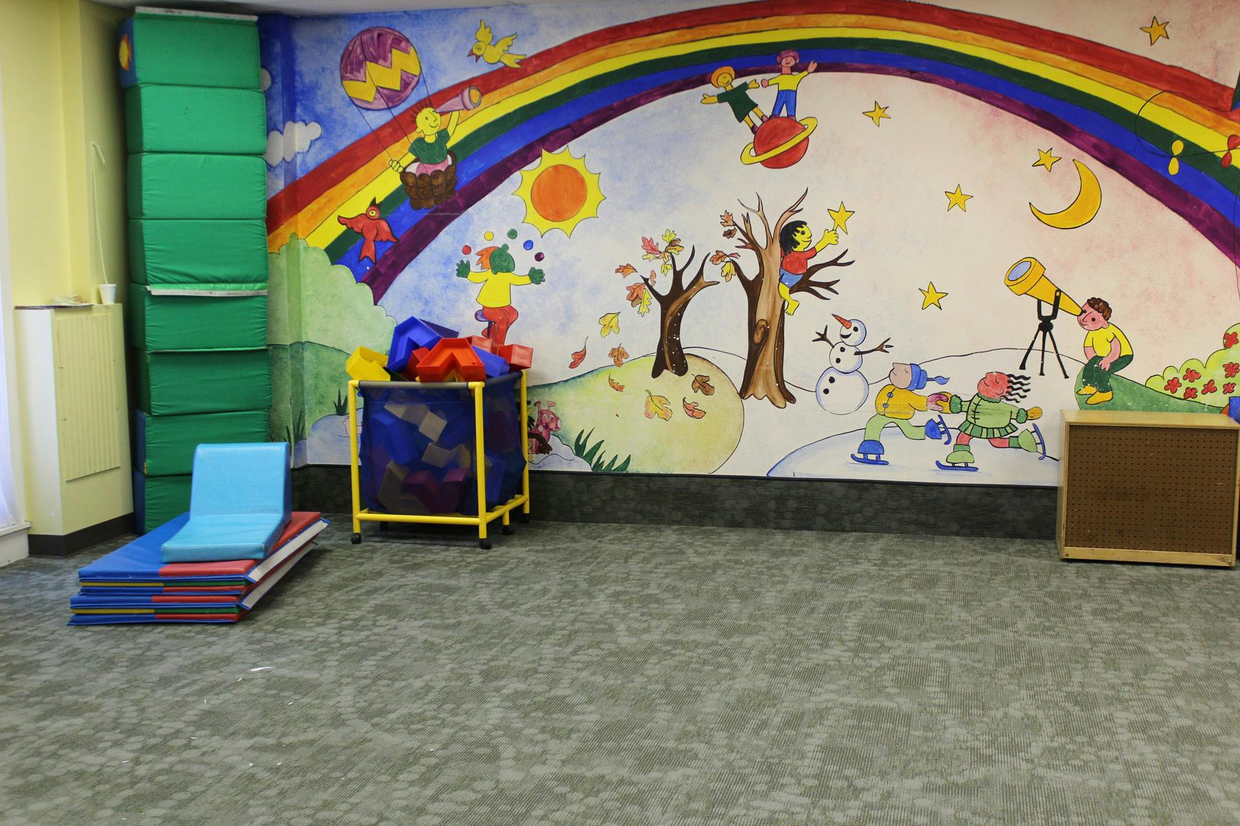 Playroom with colorful wall mural and soft play mats
