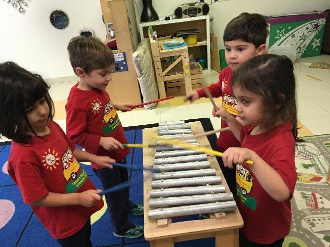 Four children playing a xylophone in a classroom