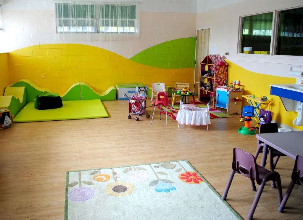 Playroom with colorful walls, small tables, chairs, and play mats