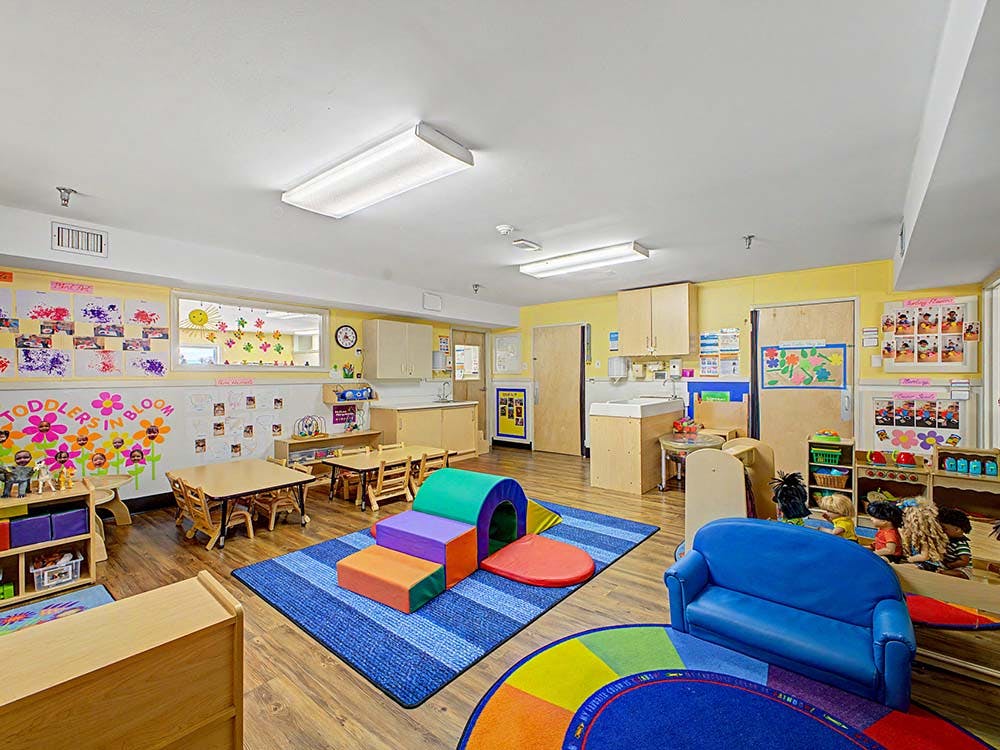 children's classroom with small tables, play mats, and a changing station