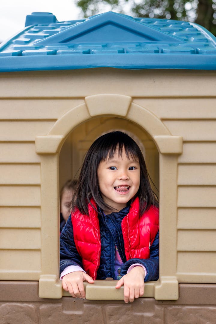 Child peeking out of a playhouse window
