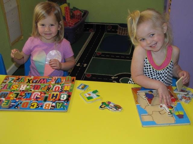 Two children playing with puzzles at a table