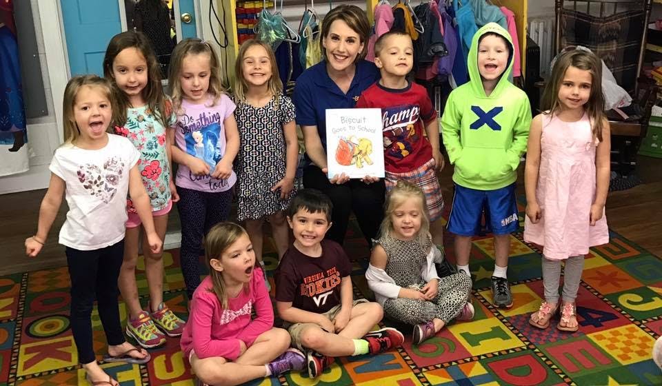 Person holding a book surrounded by children