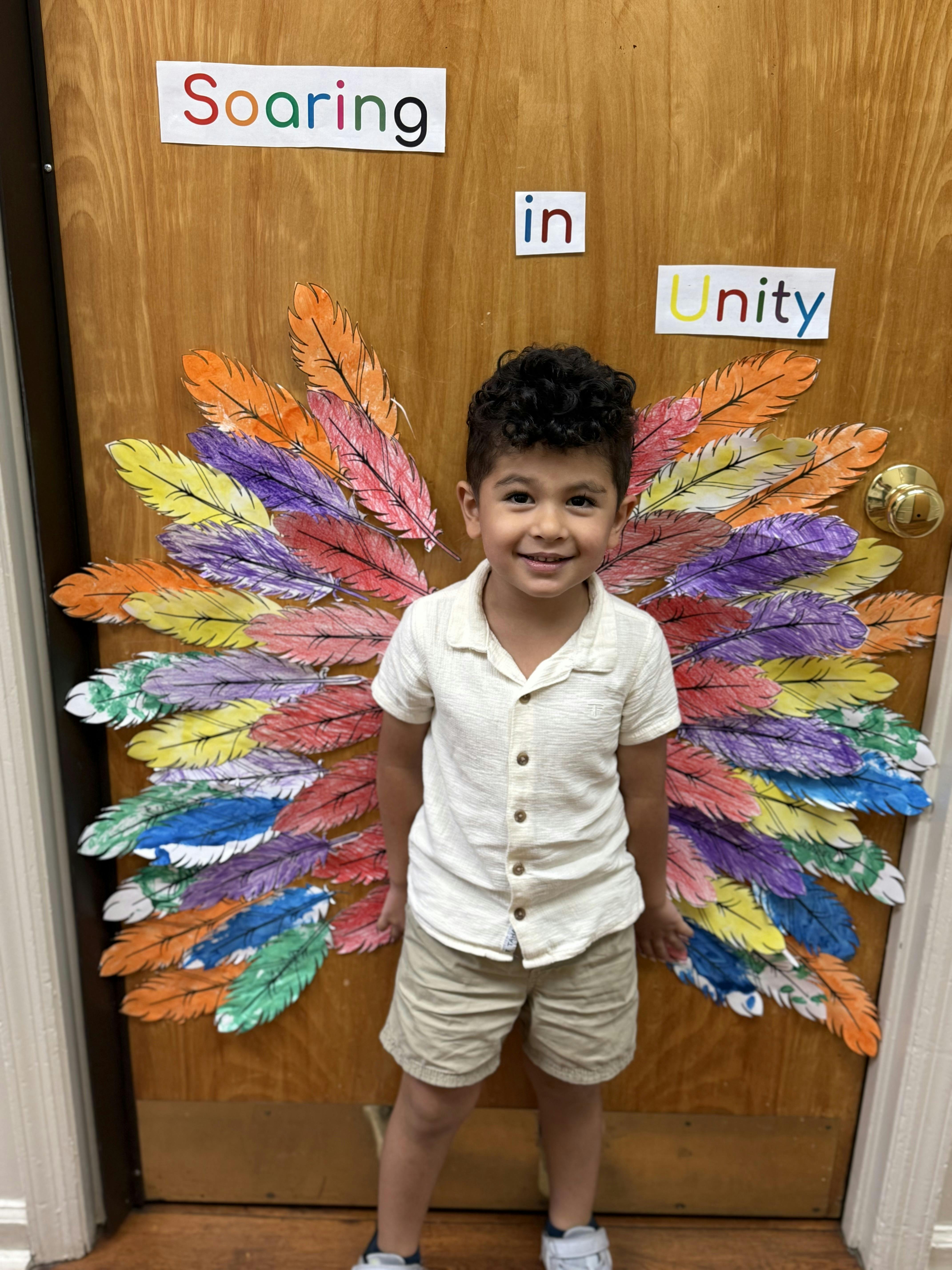 Child standing in front of a door with colorful feather decorations