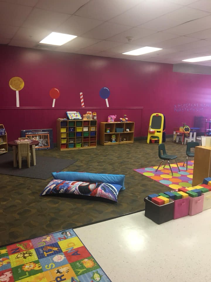 Children's play area with colorful rugs, small tables, and storage shelves