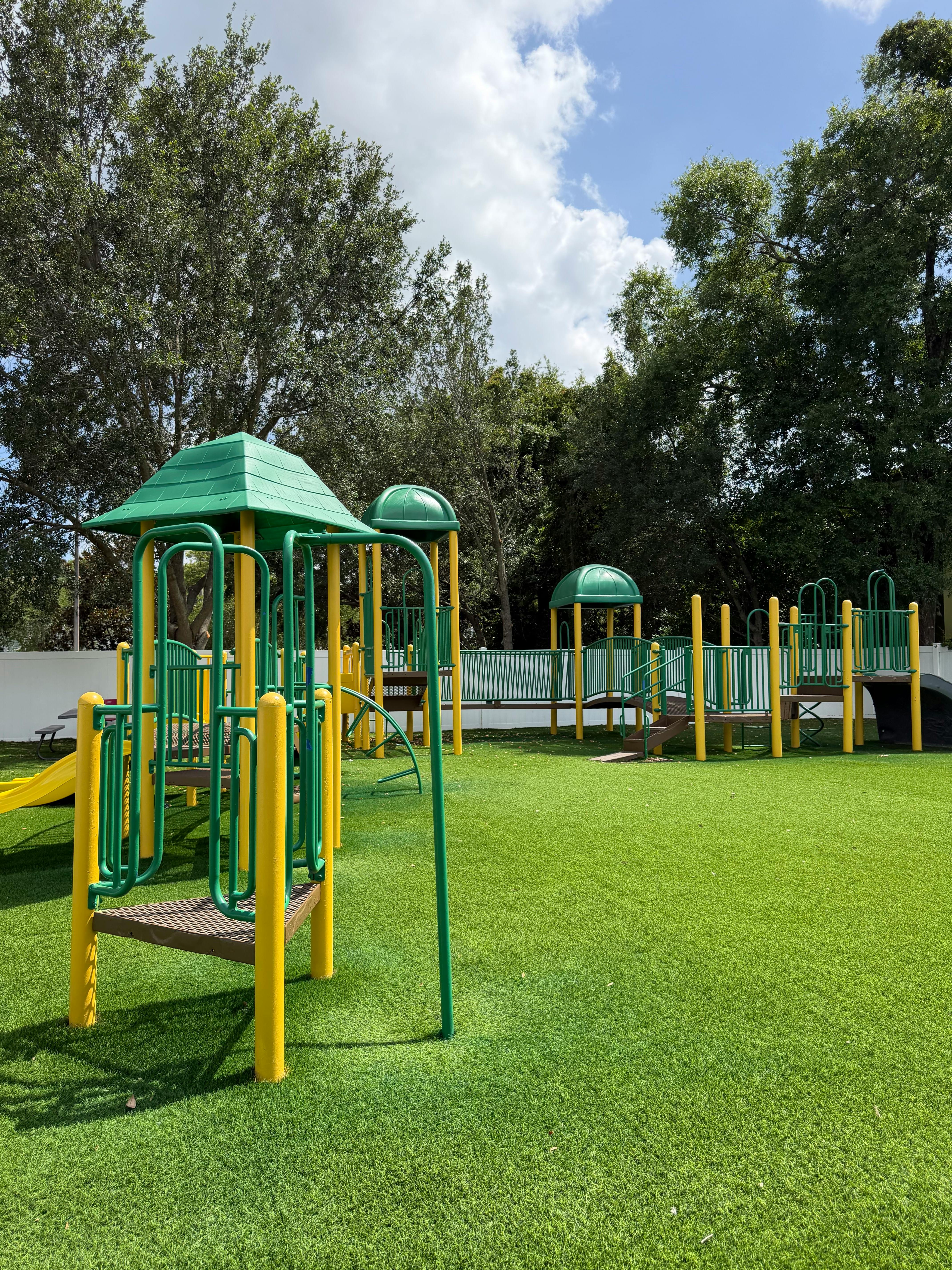 Playground equipment on a green turf field near trees