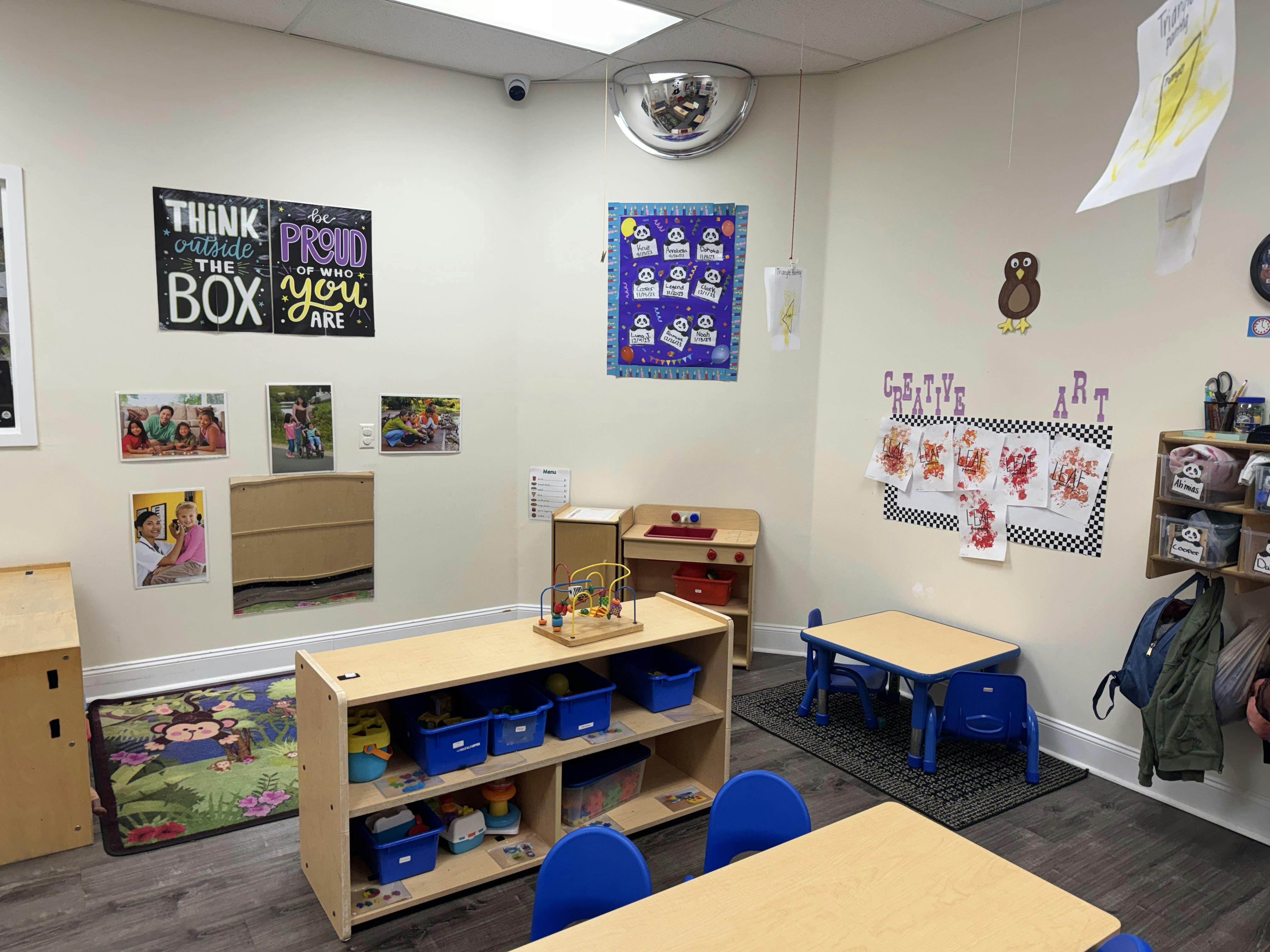 Empty classroom with small tables and chairs, shelves, and wall decorations