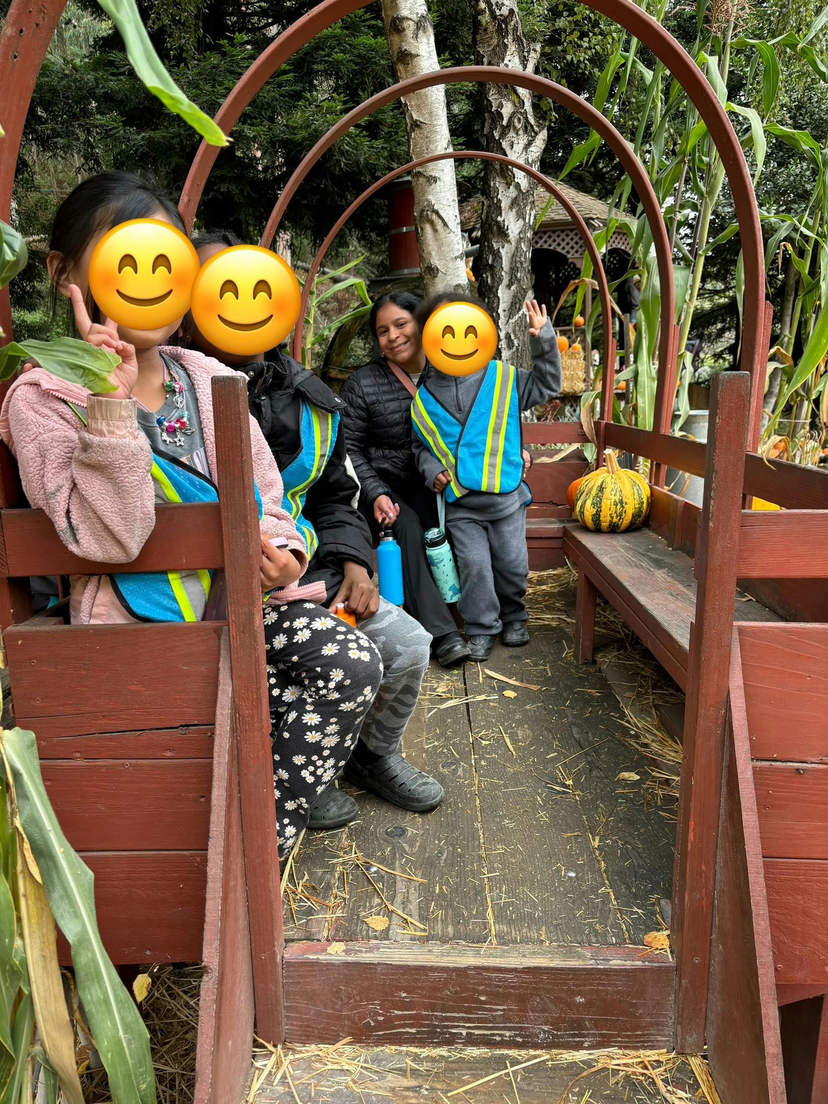 People and children sitting in a wagon with pumpkins