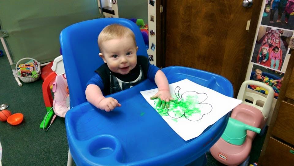 Child in high chair coloring a shamrock