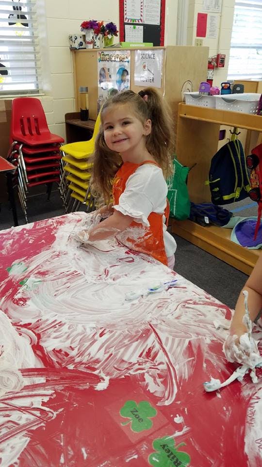 Child playing with shaving cream on a red table
