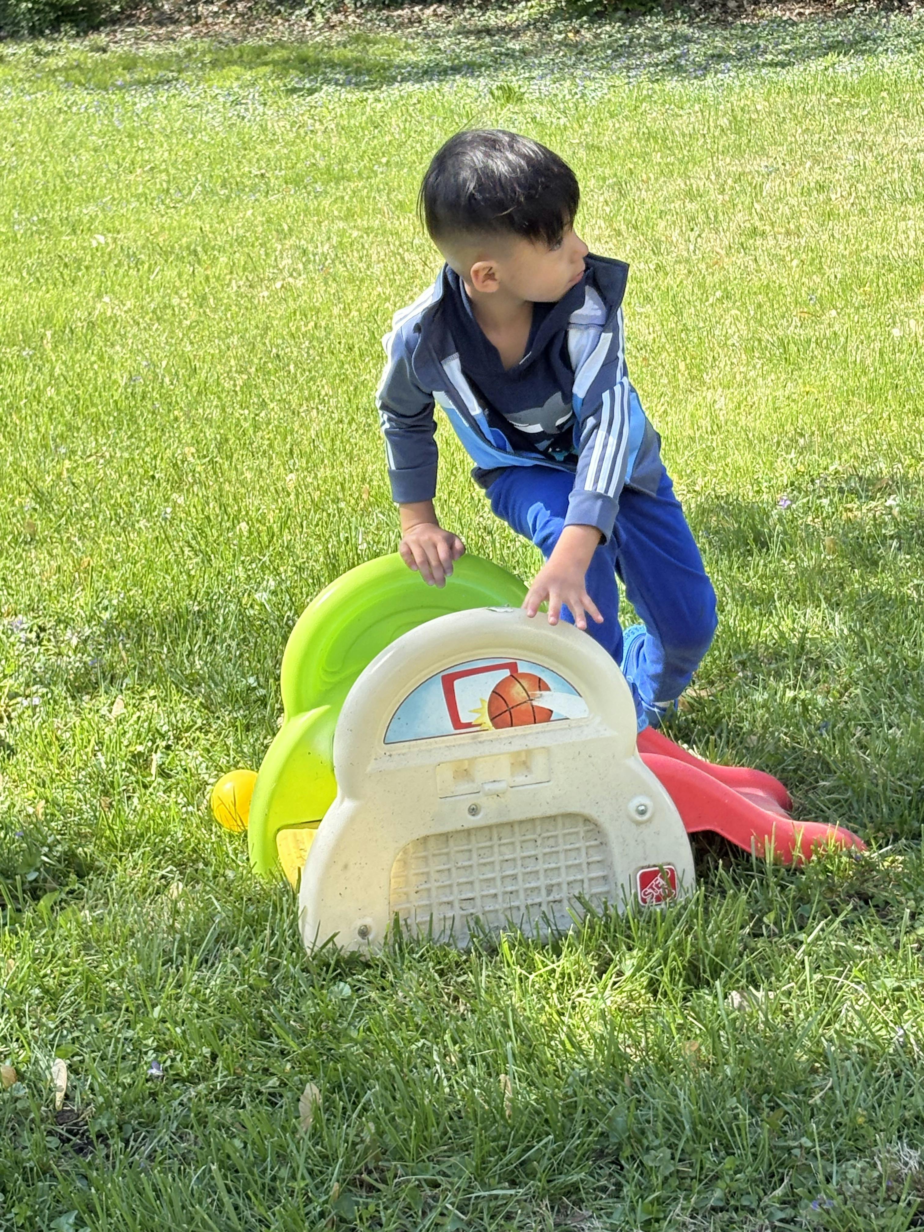 Child playing with a toy basketball hoop on grass