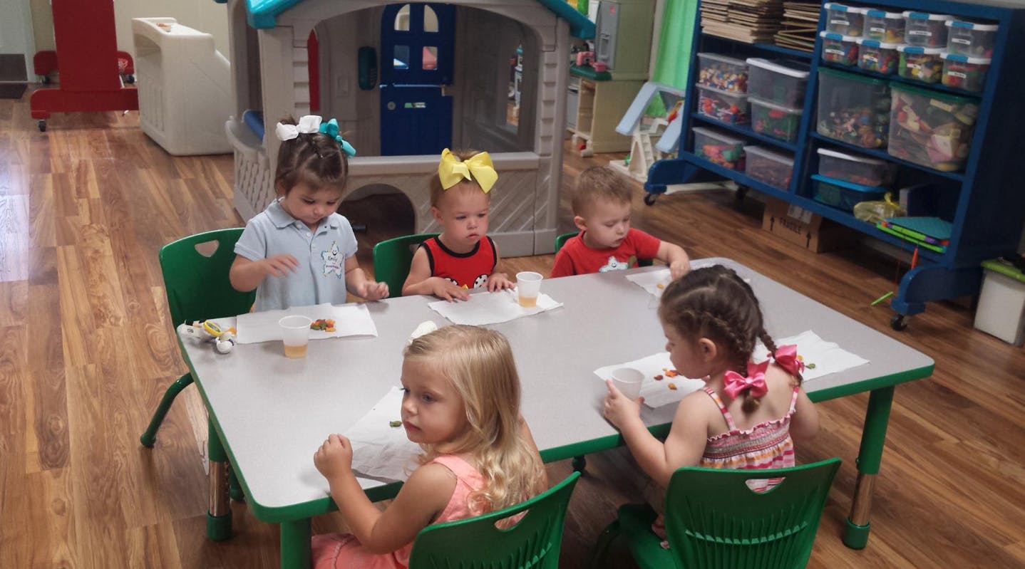 Four children sitting at a table with papers