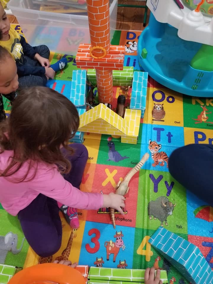 Child playing with toy blocks and a toy animal on a colorful mat