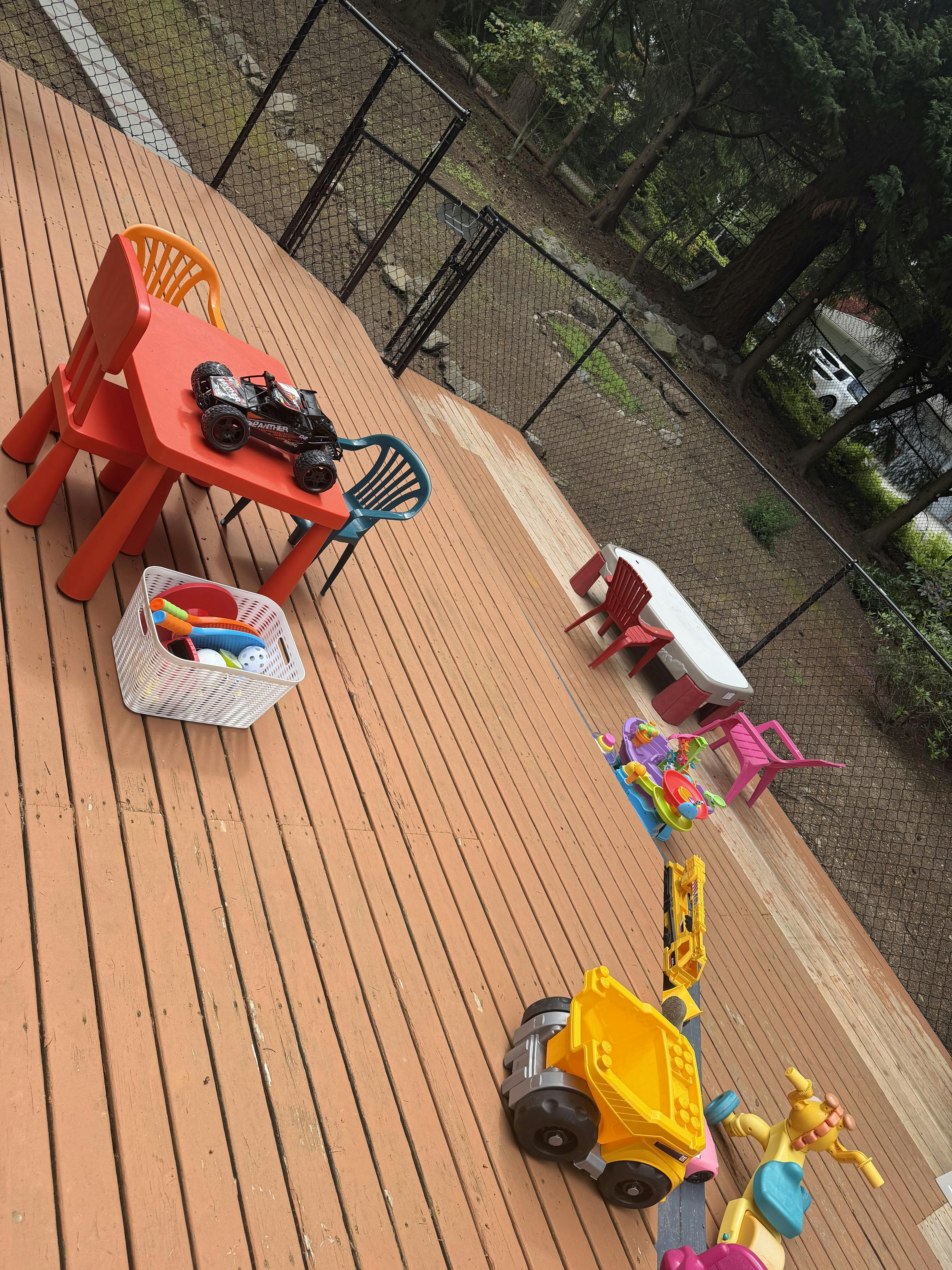 Plastic tables, chairs, and various children's toys on a wooden deck