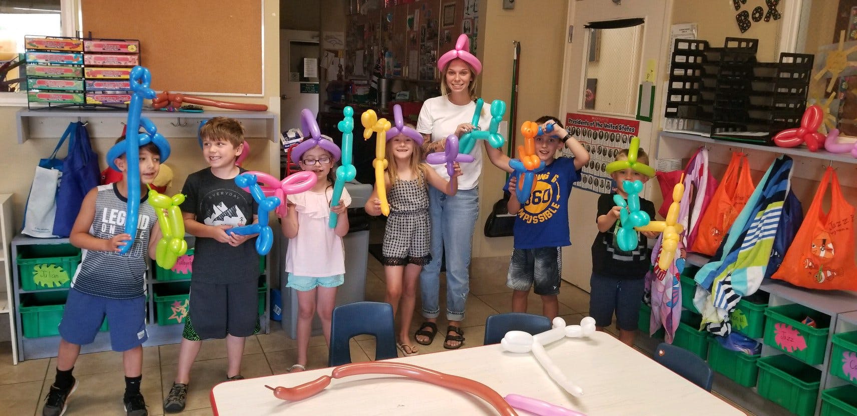 Adult and children holding balloon animals and swords in a room